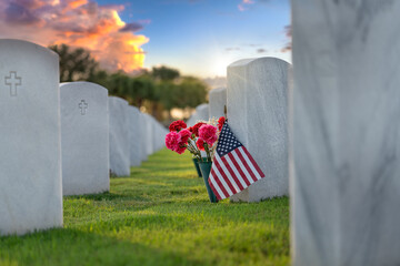Military burial headstones. Sarasota National Cemetery with rows of white tomb stones with flowers and USA flags on green grass. Memorial Day concept