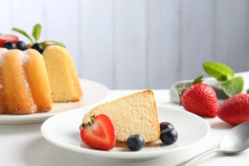 Tasty bundt cake with powdered sugar, berries and mint on white table, closeup