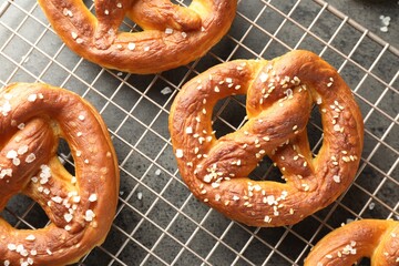 Tasty pretzels with salt on grey table, top view
