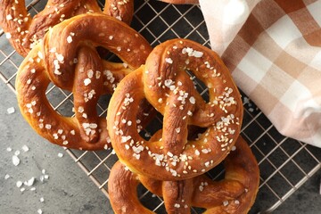 Tasty pretzels with salt on grey table, top view