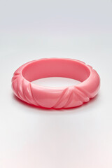Pink Decorative Bangle with Detailed Embellishments Displayed on Neutral Background..