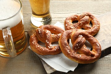 Tasty pretzels and beer on wooden table, closeup