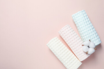 Naklejka na ściany i meble Clean waffle towels and cotton flower on light pink background, flat lay. Space for text
