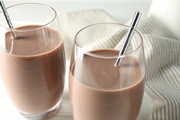 Tasty chocolate milk in glasses on table, closeup