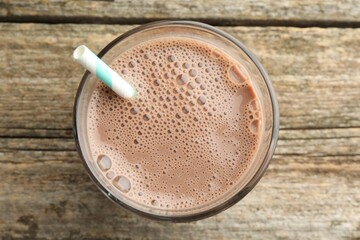 Tasty chocolate milk in glass on wooden table, top view
