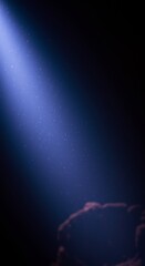 Light Beam in Darkness - A single blue light beam cuts through the dark, illuminating dust particles in its path. A blurry shape is visible at the bottom