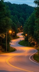 Fototapeta premium Winding Road Through Forest at Dusk - Serpentine road illuminated by streetlights winding through a lush green forest at twilight