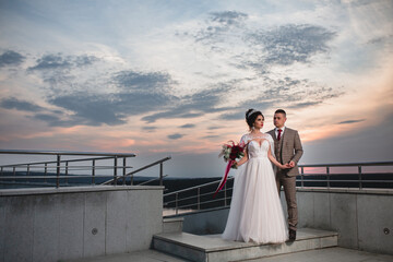 Young beautiful couple of newlywed posing in the evening against the background of an atmospheric...