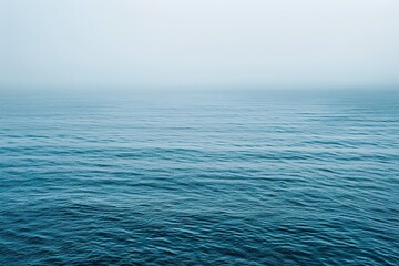 Calm blue ocean under a misty sky gentle waves reflecting the tranquil light