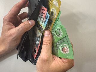 male hand holding Australian Dollar in the wallet