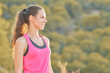 Young woman enjoying the outdoors in a pink tank top while taking in the serene landscape during sunset