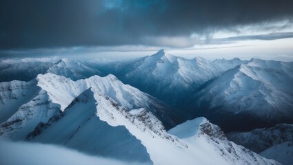 Fototapeta premium Bird's eye shot of a gorgeous mountain range blanketed in snow with clouds above