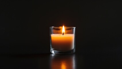 A little candle illuminates the dark, housed in a glass vessel, producing a tranquil and simple environment.