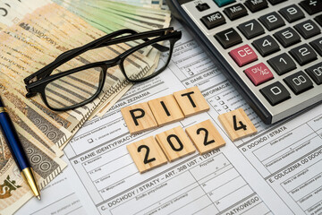 PIT 2024 on wooden blocks with pln zloty money with paper pit tax from on desk