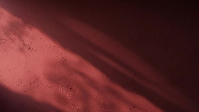 Close-up of an empty red textured wall with shadows and sparse background