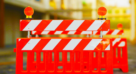 Close up of two orange and white striped barriers with lights on top in a blurred background