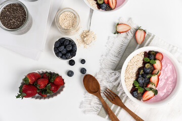 Presented by fruits putting yogurt toppings with strawberry, berry, oats, raisins and chia seed decorated by peppermint in white blow. Pink background. Set of healthy dairy product choice. Pecuniary.
