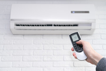 Fototapeta premium Air conditioner temperature adjustment with remote controller in room at home.