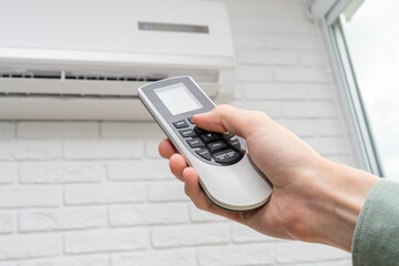 Using a remote control to regulate the temperature of a wall-mounted air conditioner