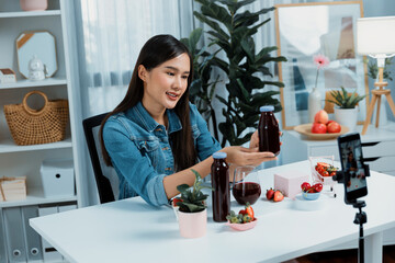 Smiling young beautiful Asian reviewing tasty mixed strawberry and cherry juice detox drinks, showing healthy product to promote for special promotion selling on social media online record. Stratagem.