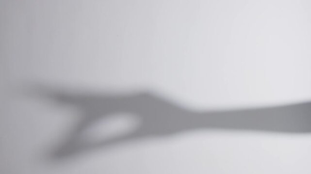 Grayscale shot of a blurry shadow puppet of a hand against a white background