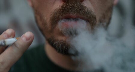 Man smoking cigarette on blurred background, closeup
