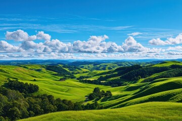 Naklejka premium Green hills landscape under bright sky with fluffy clouds