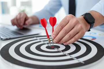 Man with dart aiming at dartboard while working indoors, closeup
