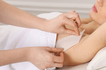 Woman undergoing wax epilation procedure in beauty salon, closeup