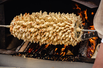 Preparing Lithuanian tree cake, šakotis or baumkuchenas, Polish sękacz, Belarusian bankucha, German baumkuchen made of butter, egg whites and yolks, flour, sugar, and cream, cooked over an open fire