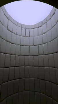 Low-angle, wide view of an arched chamber featuring soft, padded rectangular panels lining the walls and ceiling. A bright opening at the apex illuminates the interior of this unique, insulated