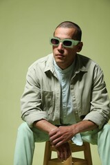 Fototapeta premium Fashionable portrait of handsome man in stylish outfit on green background