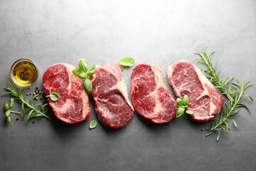 Pieces of raw beef meat and spices on grey table, flat lay