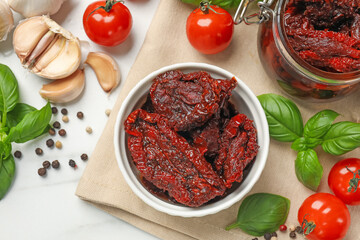 Delicious sun dried tomatoes, fresh vegetables, basil and garlic on white table, flat lay