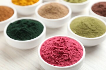 Different superfood powders on white wooden table, closeup