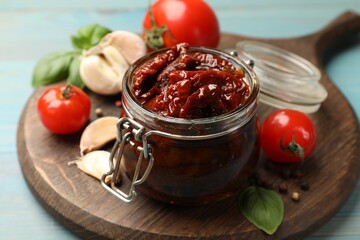 Tasty sun dried tomatoes, fresh vegetables and peppercorns on light blue wooden table, closeup