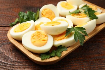 Boiled eggs and parsley on wooden table, closeup
