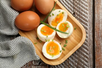 Soft boiled eggs with green onions on wooden table, top view