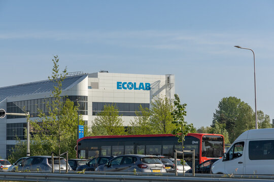 Modern Ecolab office building with logo in view, located in the Netherlands, surrounded by trees and traffic on a sunny day with clear blue sky. Oegstgeest, the Netherlands. 2 May 2025.