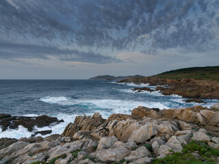 Rocas, mar y nubes. Paisaje de costa con acantilados, mar con oleaje y un cielo con nubes azules y grises
