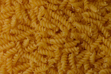 Golden fusilli pasta covering the frame. Warm light and soft shadows highlight the spiral texture of this classic Italian pasta.