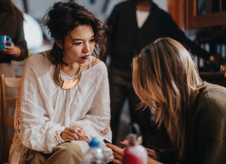 Two women engaging in a deep conversation in a cozy, casual group setting indoors.