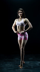 Obraz premium Young beautiful fitness woman on a black background. Fitness girl, female bodybuilder on a dark background