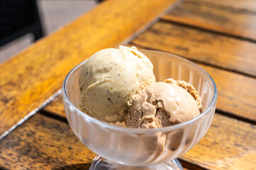 Two scoops of icecream in a glass bowl on a wooden table in Kruibeke, East Flanders, Belgium