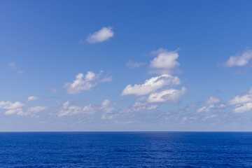 Obraz premium Serene Blue Ocean Under a Clear Sky with Fluffy White Clouds