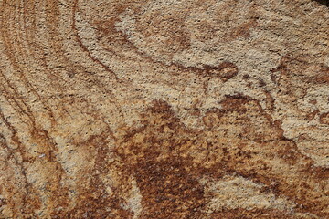 Natural texture of granite stone displays warm earth tones and lines in a close up view