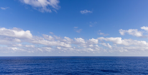 Obraz premium Blue Ocean Horizon Under a Vibrant Sky with White Clouds