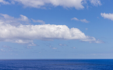 Obraz premium Blue Sky Over Calm Ocean with Large Fluffy White Clouds