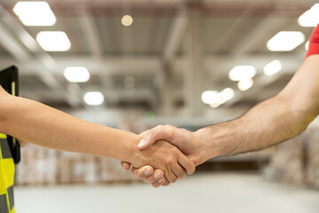 Colleagues shake hands in the warehouse, symbolizing partnership and mutual respect in a...