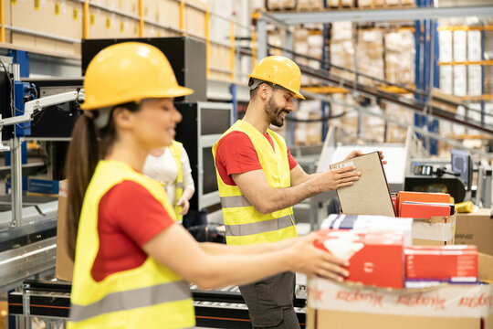 Warehouse workers are focused on organizing boxes, emphasizing teamwork and the importance of efficient logistics.